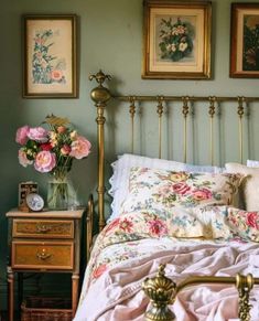 there is a bed with pink flowers and pictures on the wall above it, along with two nightstands