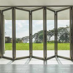 an open room with multiple doors and windows on the outside, looking out onto a grassy field