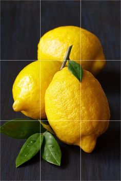 two lemons with green leaves sitting on a table next to each other in front of a grid