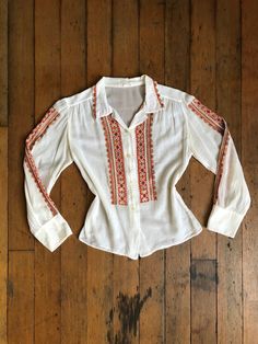 "Gorgeous long sleeve blouse from the 1950s with vibrant embroidery. Buttons up the front with hidden snaps to keep it closed when worn.  Label: there's a label but the words are long gone.  Measurements: { xsmall } Bust: 32\"  Waist: 30\"  Length: 31\" Sleeve Length: 20.5\" Condition: excellent vintage condition with minor signs of wear - sold as found. washed and ready to wear ☆Shop☆ http://www.trunkofdresses.com/" Vintage White Blouse With Intricate Embroidery, Vintage Embroidered Long Sleeve Blouse, Fitted Long Sleeve Vintage Embroidered Top, Vintage Floral Embroidered Blouse For Fall, Vintage Fitted Blouse With Intricate Embroidery, Fitted Vintage Blouse With Intricate Embroidery, Vintage Cotton Tops With Intricate Embroidery, Retro Long Sleeve Top With Floral Embroidery, Vintage Embroidered Fall Shirt