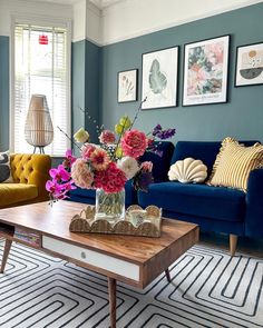 a living room filled with furniture and flowers on top of a coffee table in front of a blue couch