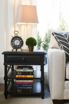 a living room with a white couch and a black end table next to a window