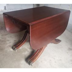 a wooden desk sitting on top of a floor next to a brick wall and cement floor