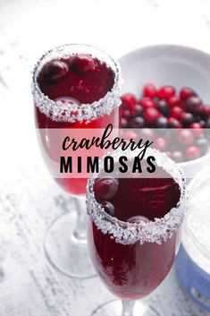 two glasses filled with cranberry mimosa on top of a white table