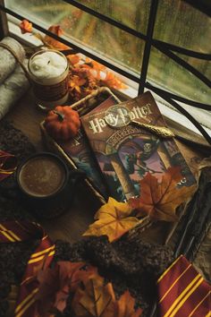 a harry potter themed table with books, candles and autumn leaves on the floor next to it