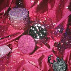 several different types of items on a pink cloth with lights in the background and some glitter