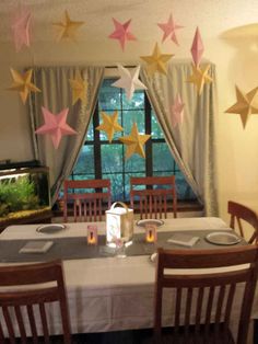 the table is set with place settings for two people to sit at, and there are paper stars hanging from the ceiling