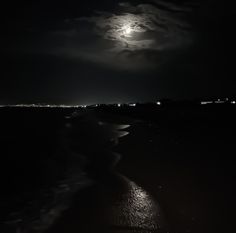 the moon is shining in the dark sky over the water at night on the beach