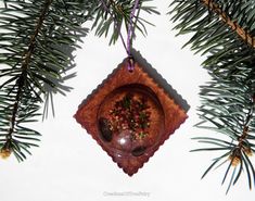 an ornament hanging from a pine tree with berries and leaves in the center