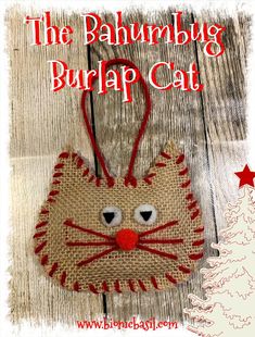 a burlap cat ornament hanging on a wooden background with the words, the bauhmug burlap cat