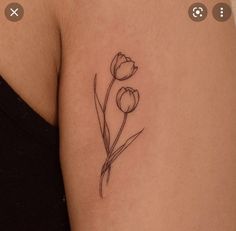 a small flower tattoo on the back of a woman's left arm and shoulder