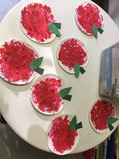 paper plates with red flowers on them sitting on a table in front of some books