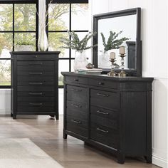 a black dresser and mirror in a room with large windows on the wall, along with other furniture