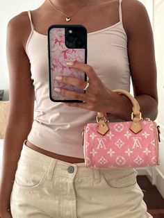 a woman holding a pink purse and looking at her cell phone