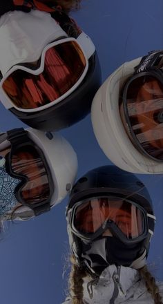 three snowboarders wearing goggles and helmets against a blue sky