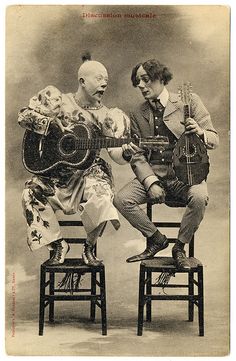 an old photo of two people sitting on chairs with guitars in their hands and one playing the guitar