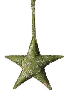 a green and white star ornament hanging from a string on a white background