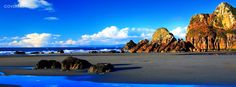 the beach has many rocks on it and blue water in the foreground is an ocean with white clouds