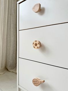 a white dresser with three drawers and knobs