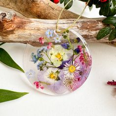 a glass ornament filled with flowers on top of a branch