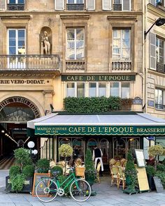 a green bicycle parked in front of a cafe with plants growing out of it's windows