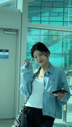 a young woman is standing in front of a building and holding her cell phone up to her ear