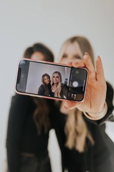 two women are taking a selfie with their cell phone in front of the camera