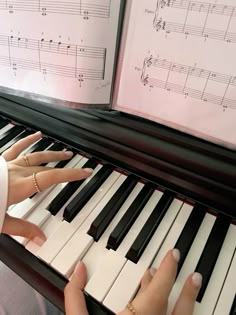 two hands playing the piano in front of sheet music