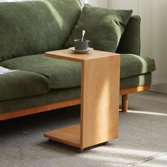 a small wooden table sitting on top of a carpeted floor next to a green couch