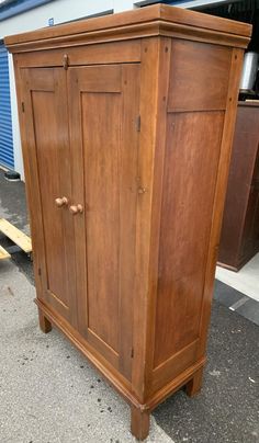 a wooden armoire sitting on the side of a road