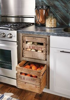 a kitchen with an oven, stove and two wooden crates filled with fruit in it