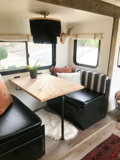 a living area with couches and a table in front of two windows on the inside of a mobile home