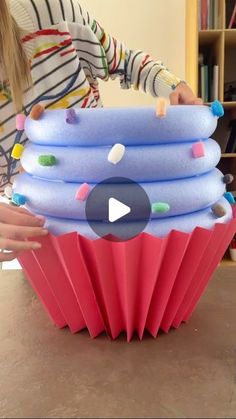 a woman is holding a giant cupcake with sprinkles on it's sides