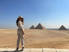 a woman standing in front of three pyramids