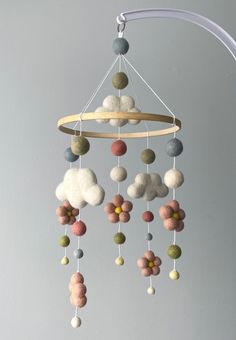 a mobile made out of felt balls hanging from a white ceiling fixture with a circular wooden rod