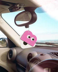 a car dashboard with a pink heart shaped tag hanging from the dash