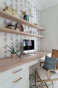 a desk with a computer on top of it next to a chair and wallpaper