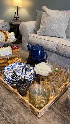 the tray is full of desserts and drinks on the coffee table in the living room