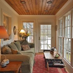 a living room filled with furniture and windows next to a red rug on top of a wooden floor