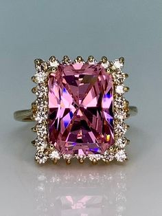 "Stunning large pink tourmaline and genuine diamonds runway-style cocktail ring! This ring is approximately a size 9.25. It measures approximately 18mm tall by 16mm wide at the head. The band measures approximately 2mm wide at the back. The large emerald-cut pink tourmaline center stone measures approximately 14.5mm tall by 9.5mm wide (~6 carats or larger). It is surrounded by 26 sparkling white genuine diamonds! At approximately 2mm each, there is a total of 3/4 CTW or greater of genuine diamon Luxury Pink Sapphire Cluster Ring As Gift, Luxury Pink Classic Style Gemstones, Pink Diamond Rings With Square Cut, Pink Diamond Square Cut Rings, Pink Diamond Ring With Halo Setting For Formal Events, Pink Diamond Ring With Halo Setting For Formal Occasions, Formal Pink Rings With Halo Setting, Square Cut Pink Diamond Ring, Formal Pink Halo Setting Rings