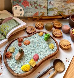 an open book on a table with wooden spoons and other items in front of it