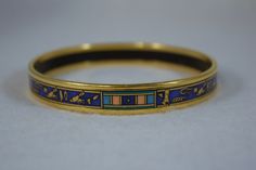 "C1980's, Michaela Frey gold plated Egyptian Revival bangle bracelet This is a 7-1/2\" bracelet, 3/8\" wide the bracelet is used and shows some wear along the edge (very small scuff or impressions in the gold) Repeating Egyptian designs on band" Antique Gold Enamel Bracelets, Collectible Enamel Bangle Jewelry, Collectible Yellow Gold Bangle Bracelet, Gold Enamel Bangle Bracelet, Gold Enamel Bangle Bracelets, Formal Enamel Bangle Bracelet, Traditional Gold Enamel Bangle, Yellow Gold Bangle Bracelet, Symbolic Ceremonial Bangle Bracelets