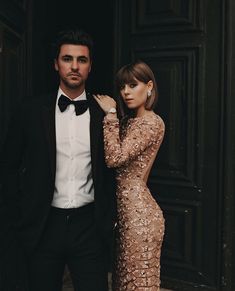 a man in a tuxedo standing next to a woman wearing a gold dress