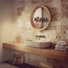 a bathroom with stone walls and a round mirror on the wall, along with a sink