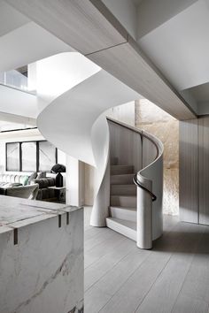 an instagramted photo of a spiral staircase in a modern house with marble floors and walls