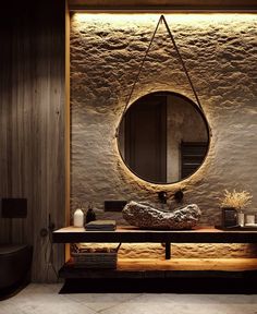 a bathroom with stone walls and a round mirror on the wall, along with a wooden bench