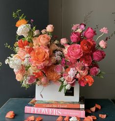 an arrangement of flowers and books on a table