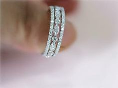 a woman's hand holding two white gold and diamond bracelets on her finger