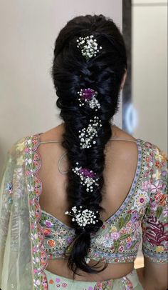 the back of a woman's head with long black hair and flowers in her hair