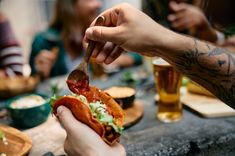 a person is eating a hot dog at a table with other people sitting around it